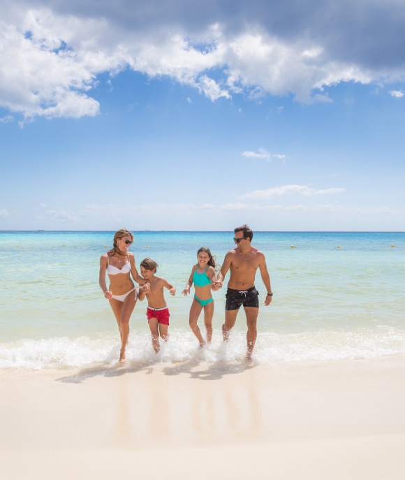 Familia de papá,mamá hijo e hija caminando en la playa